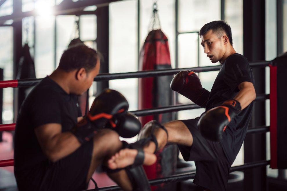 Muay Thai kickboxing trainer working with kickboxer. Muay Thai kickboxing trainer and kickboxer